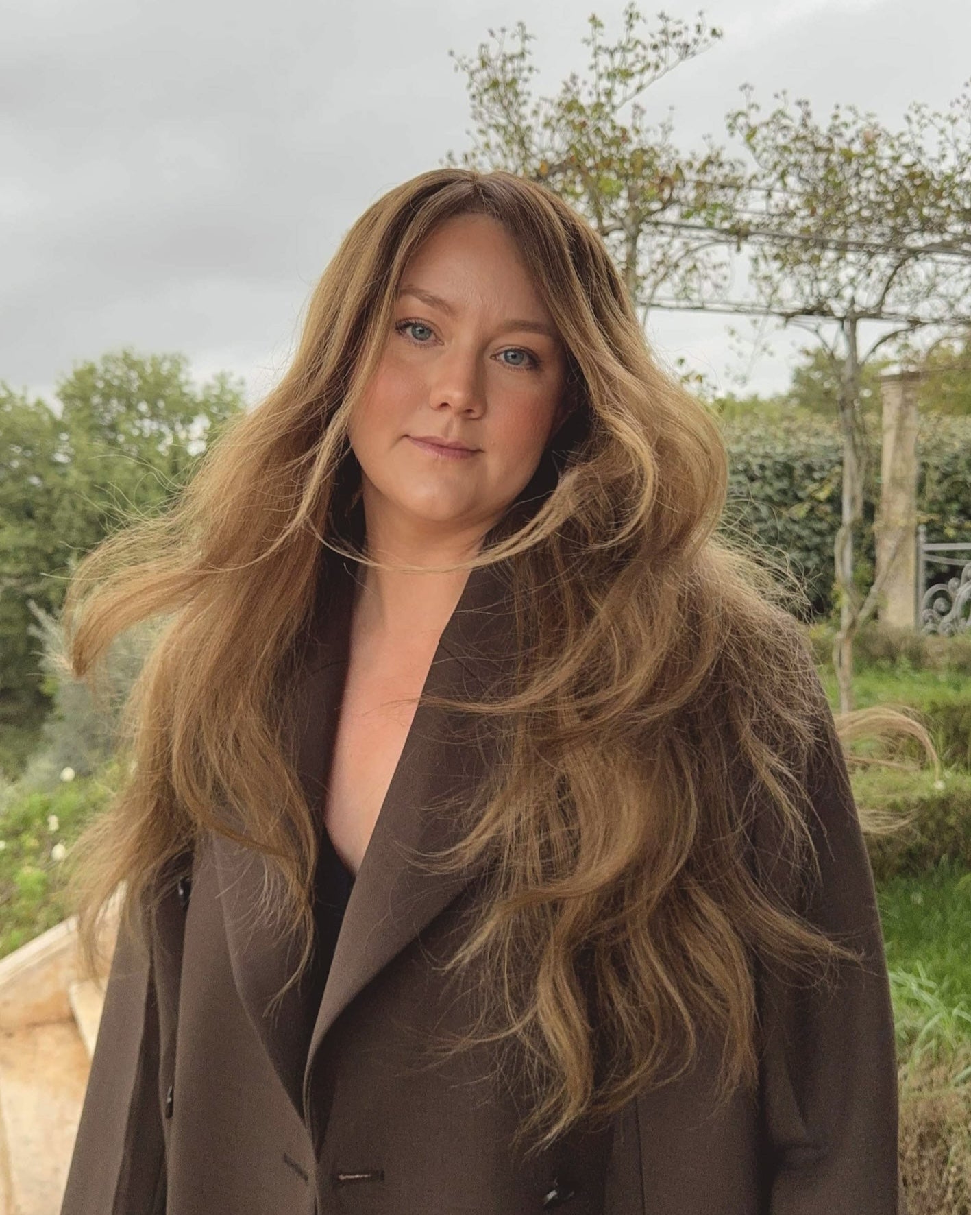 Woman wearing a long BHBD Elena wig with blended balayage, soft caramel brown tones and cool medium brown lengths. 